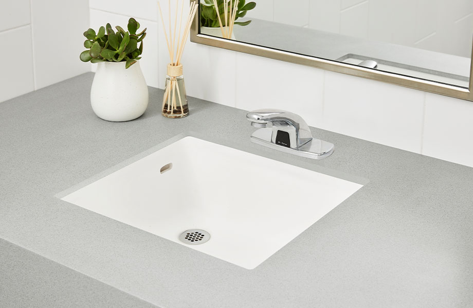 Bathroom with mirror and 415 Luna Steel solid surface countertop and integrated sink support cleanliness in hospitality design